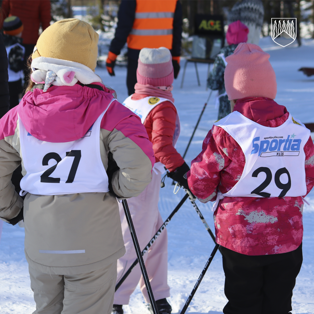 Kuvassa kaksi lasta hiihtokilpailuissa lähtöä odottomassa.