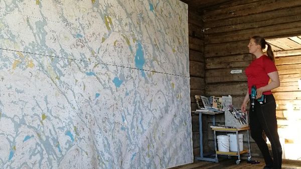 Nainen porakone kädessä valtavan kartan edessä