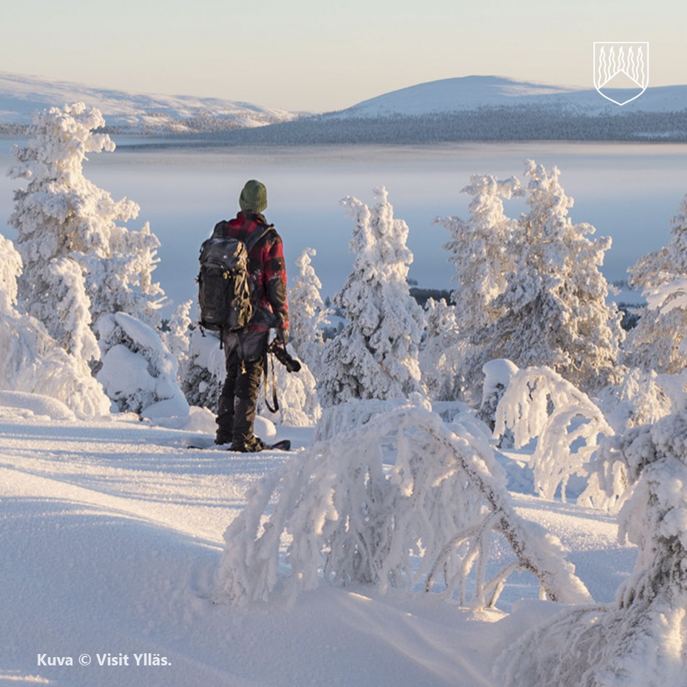 Kuvassa henkilö talvisessa maisemassa ihastelemassa tuntureita.