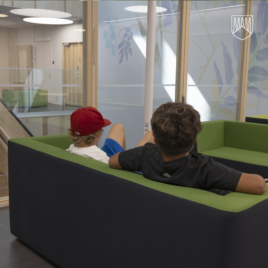 Kaksi poikaa istumassa uuden koulun sohvalla.